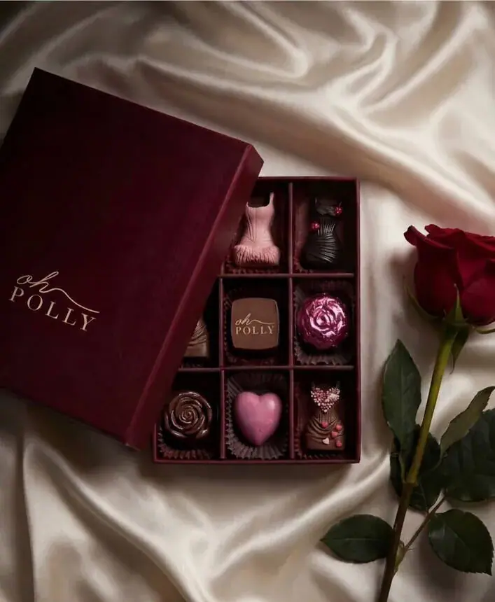 Gifting campaign image for a chocolatier: burgundy box of pralines on silk with a rose