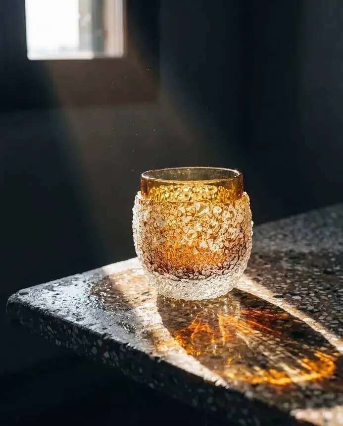 Product campaign image for a glass maker: amber Murano glass on stone in low sun